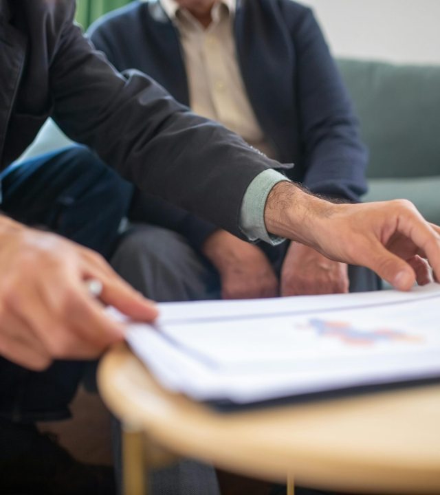 Two men discussing documents during a business meeting, focusing on paperwork.